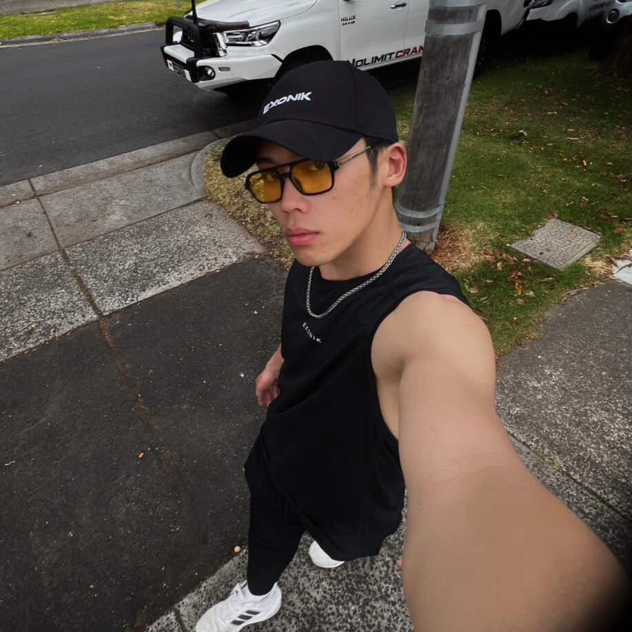 Person taking a selfie on a sidewalk with vehicles in the background while wearing Exonik's activewear