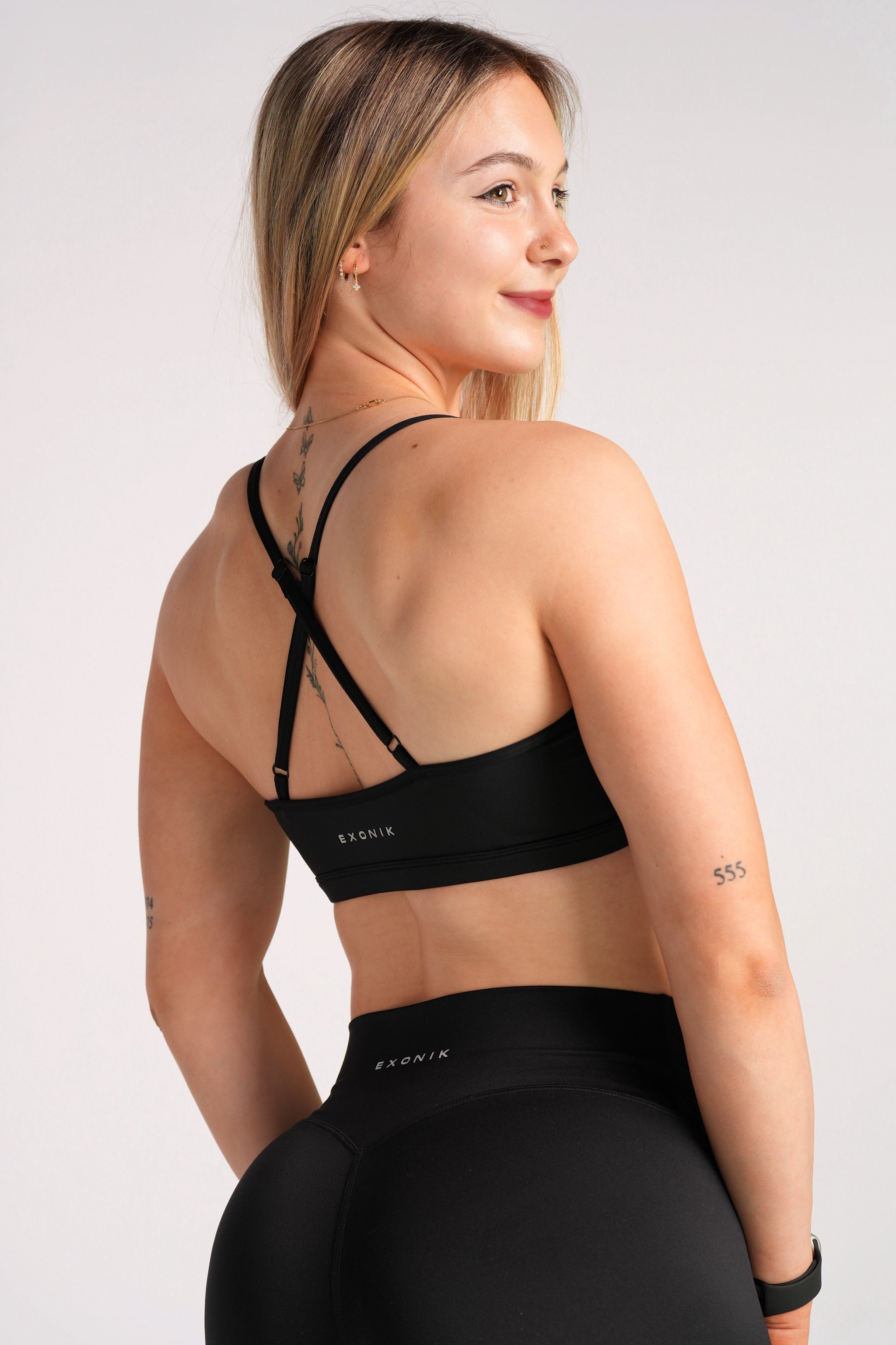 Half-body back view of a model wearing the Exonik Luxo Freedom Bra in Black, highlighting the back strap design.