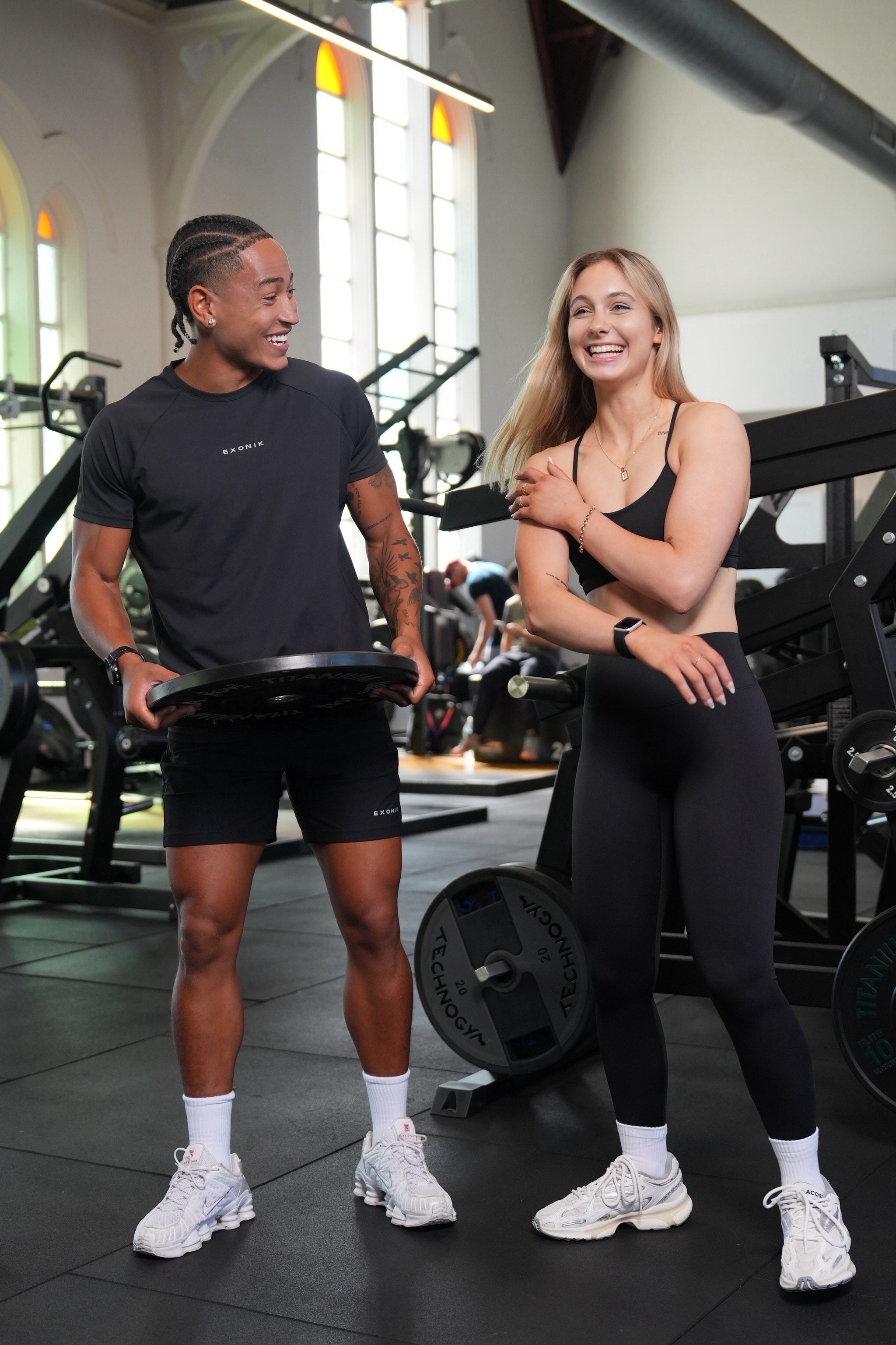 Full-body front view of a male model wearing the Exonik Systema Tee in Black in a studio setting.