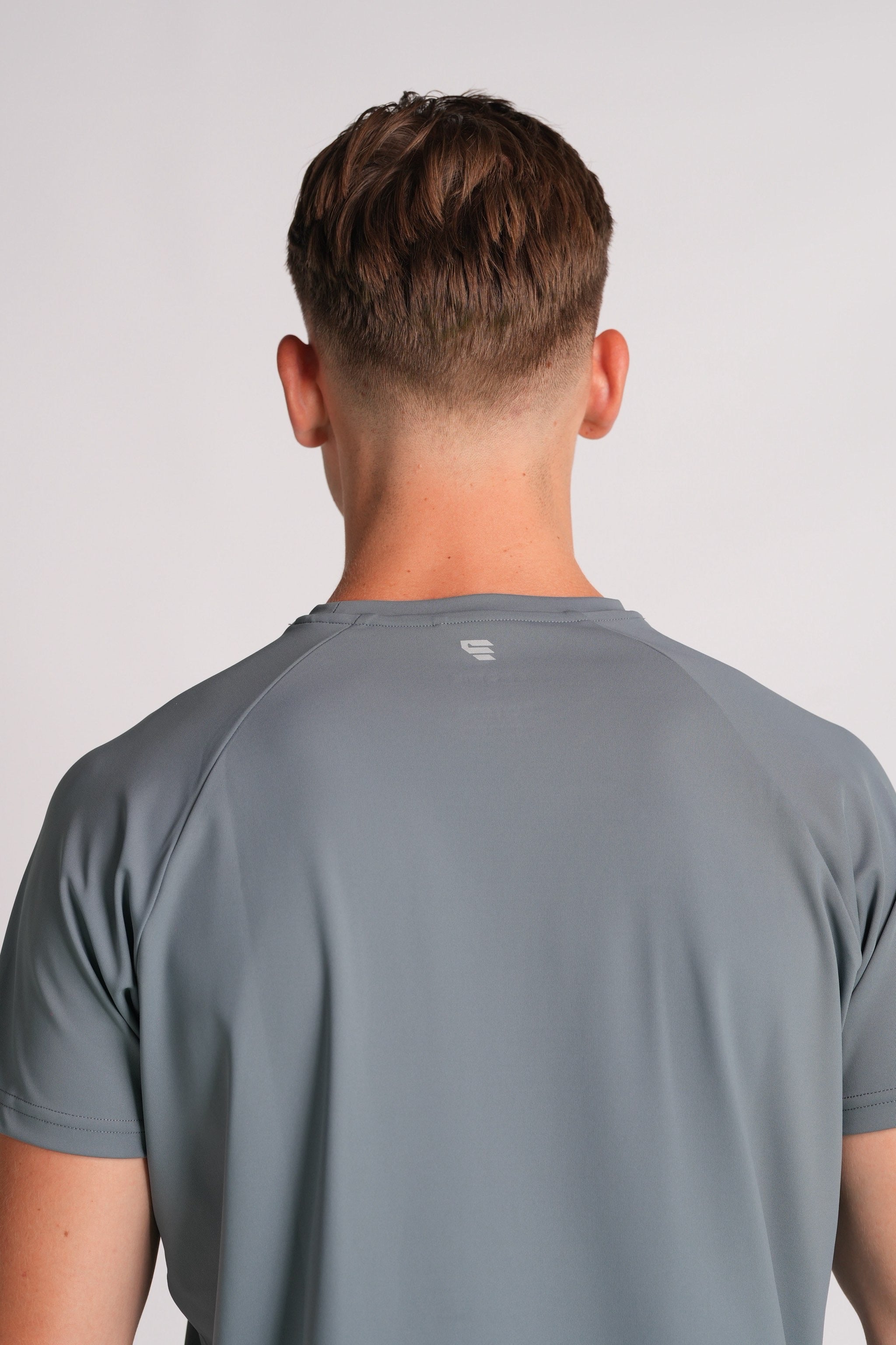 Close back shot of the Exonik Systema Tee in Basalt Grey, focusing on the back logo.