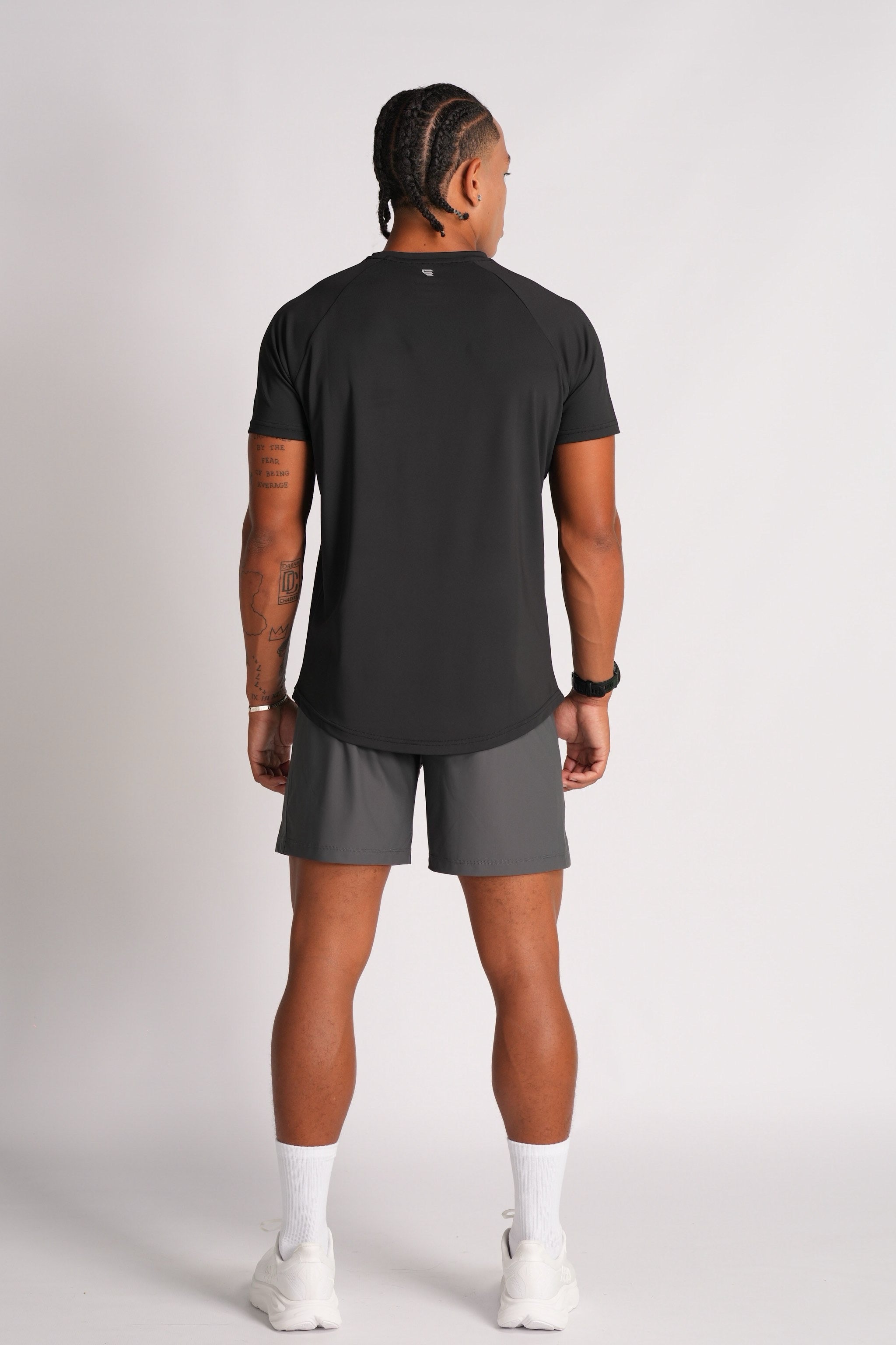 Male model wearing the Exonik Systema Tee in Black, shown in a full-body back pose against a plain studio backdrop.