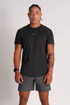 Full-body front view of a male model wearing the Exonik Systema Tee in Black in a studio setting.