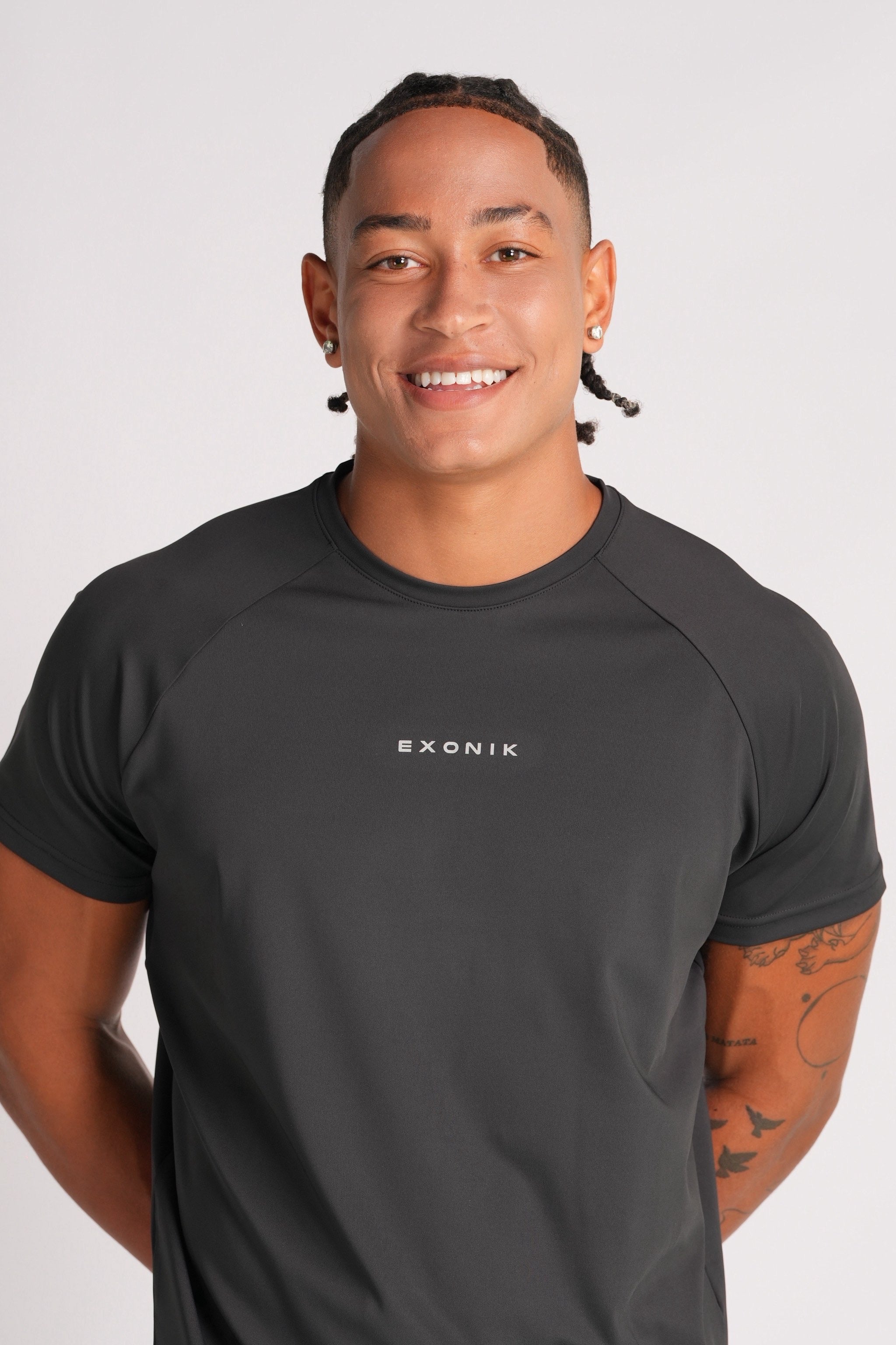 Close front shot of a male model smiling while wearing the Exonik Systema Tee in Black, with the logo in focus.